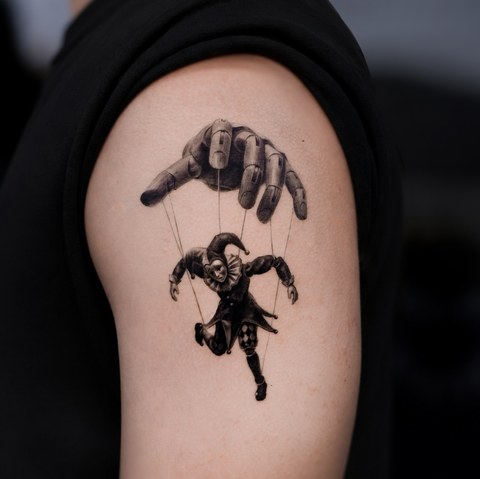 marionette puppet tattoo on the upper arm
