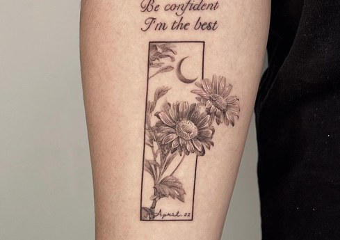 framed chrysanthemum and lettering tattoo on the forearm