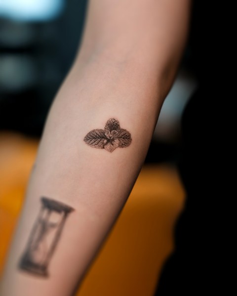 small flower and hourglass tattoo on the arm