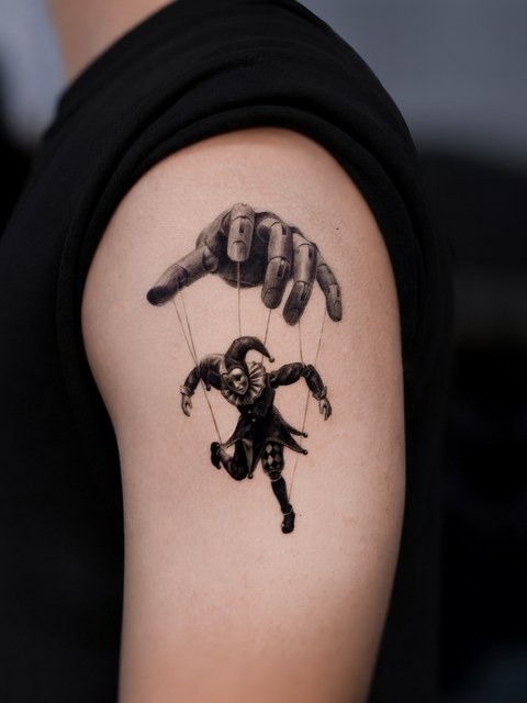 marionette puppet tattoo on the upper arm
