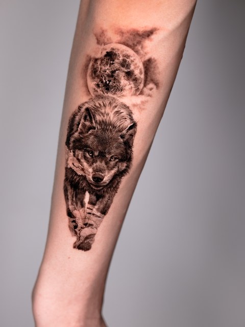 wolf and moon black and grey tattoo on the forearm