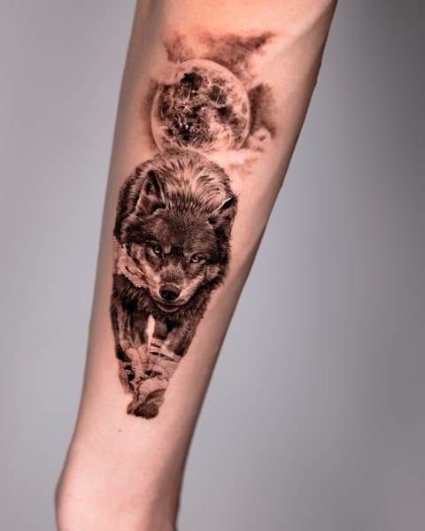 wolf and moon black and grey tattoo on the forearm