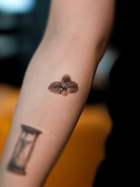 small flower and hourglass tattoo on the arm