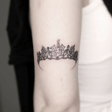 crown tattoo on the forearm