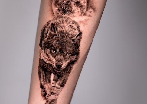 wolf and moon black and grey tattoo on the forearm