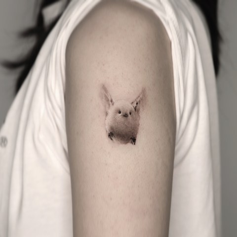 tiny bird micro tattoo on the upper arm