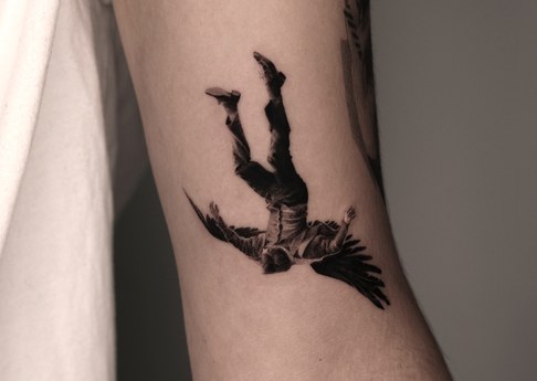 falling figure tattoo on the arm