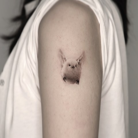 tiny bird micro tattoo on the upper arm