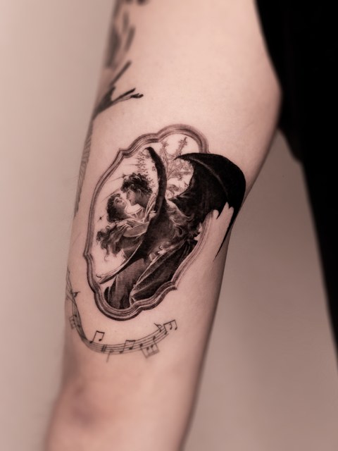 skull, flowers and lettering tattoo on the arm