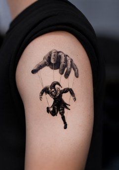 marionette puppet tattoo on the upper arm